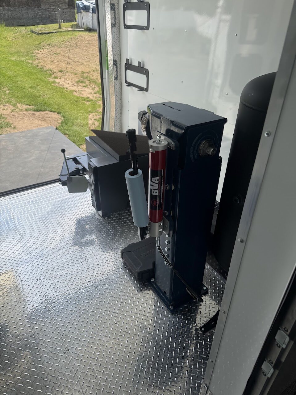 Lenco hydraulic wheel straightener beside a Custom Upfits bead breaker inside the Rim Revival trailer
